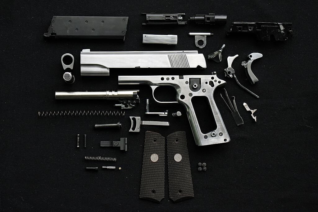 All the parts of a firearm layed out on a black background