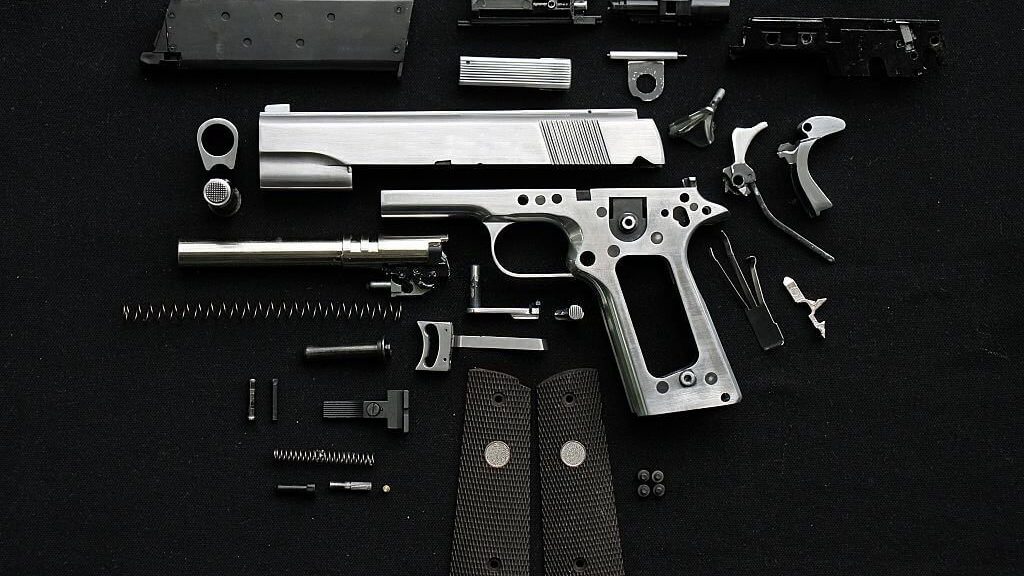 All the parts of a firearm layed out on a black background