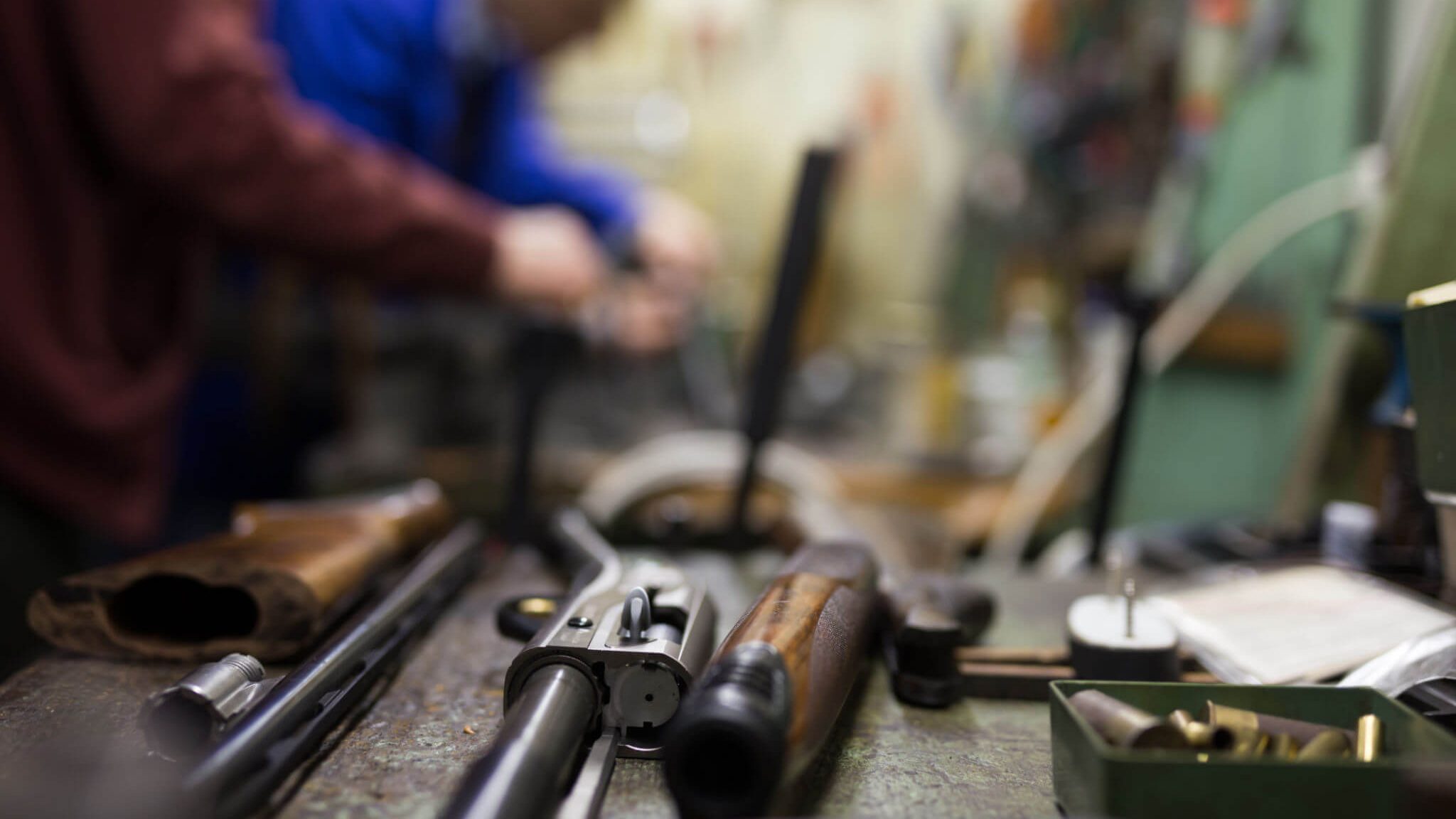 A gunsmith with firearms in the foreground