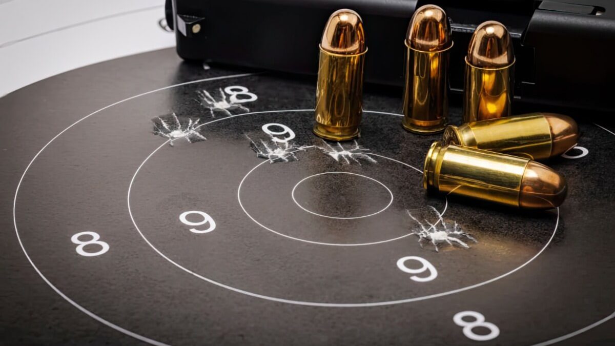 a handgun and bullets on a paper target with bullet holes